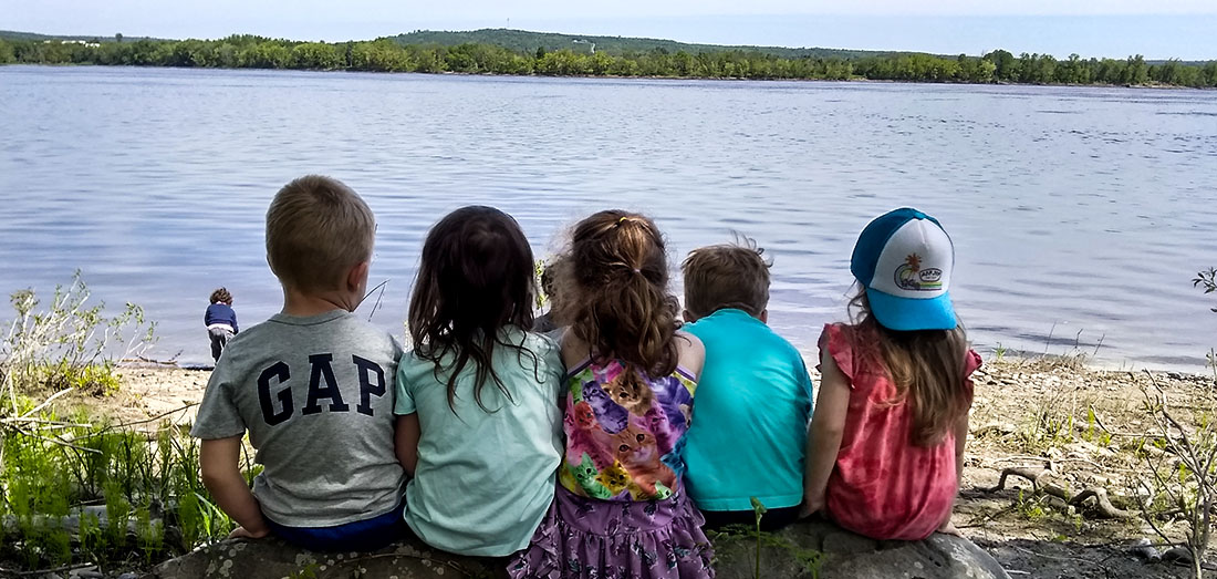 Children sitting together beside a river